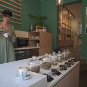 CBD shop - Frau mit grünem Oberteil rührt einen Kaffee in einem Café an. - Charlie Green GmbH 